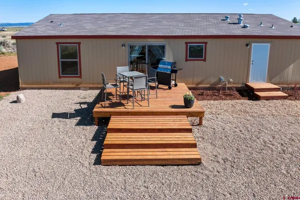 a view of a patio with table and chairs with wooden floor and fence
