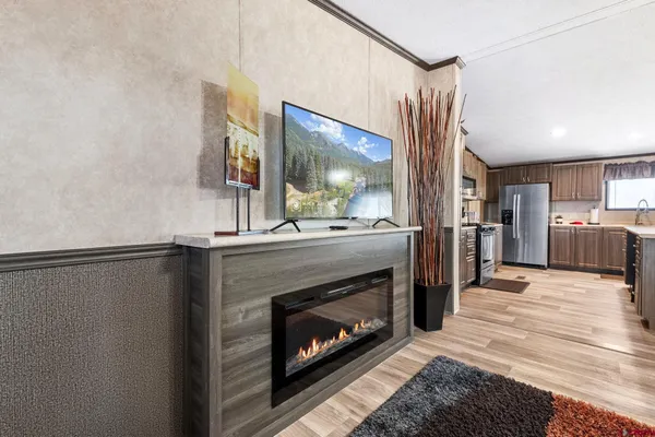 a living room with stainless steel appliances furniture a fireplace and a flat screen tv