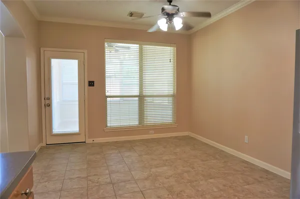 an empty room with chandelier fan and windows