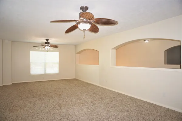 an empty room with windows and chandelier fan