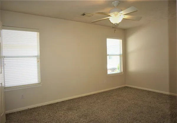 an empty room with a window and a fan