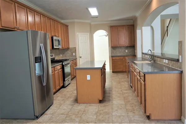 a kitchen with stainless steel appliances granite countertop a refrigerator a stove and a sink