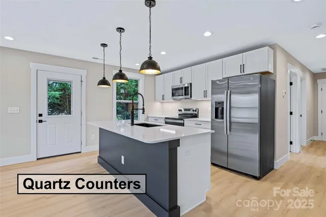 a kitchen with kitchen island a counter a refrigerator a sink a stove and a window