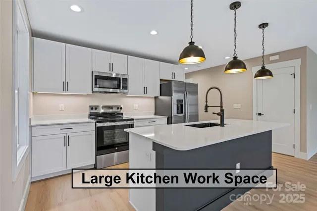 a kitchen with stainless steel appliances granite countertop a sink a stove a refrigerator and cabinets