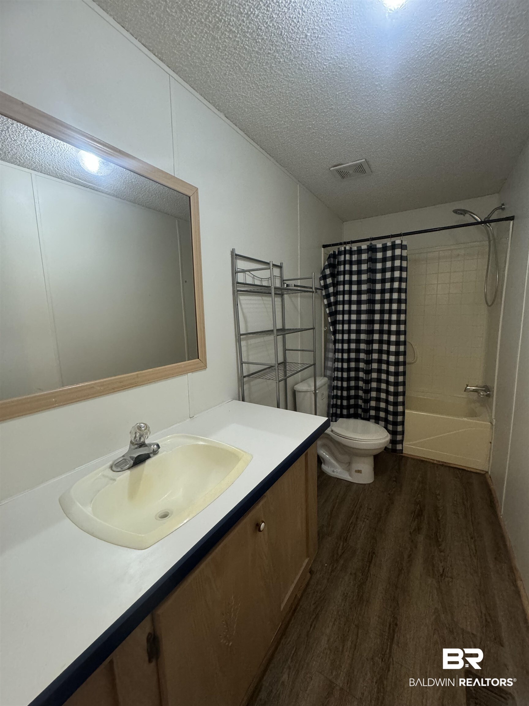 1067 County Road 7 Range, AL 36473 - Photo 9 of 30 Full bathroom featuring shower / tub combo, a textured ceiling, wood-type flooring, toilet, and vanity