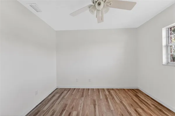 an empty room with wooden floor closet and windows