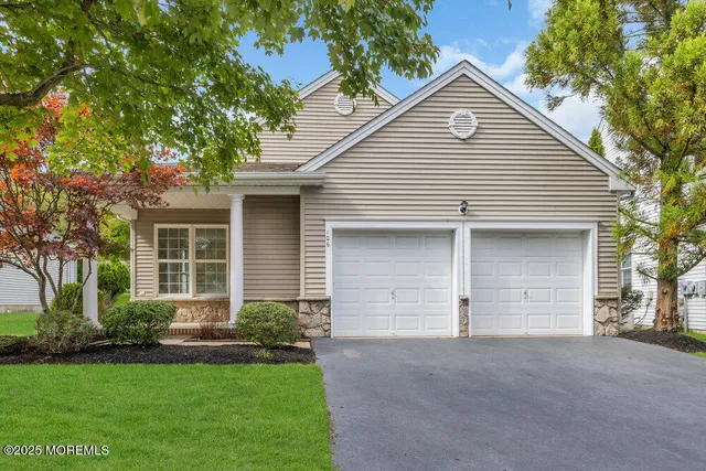 a view of a white house with a small yard and a large tree