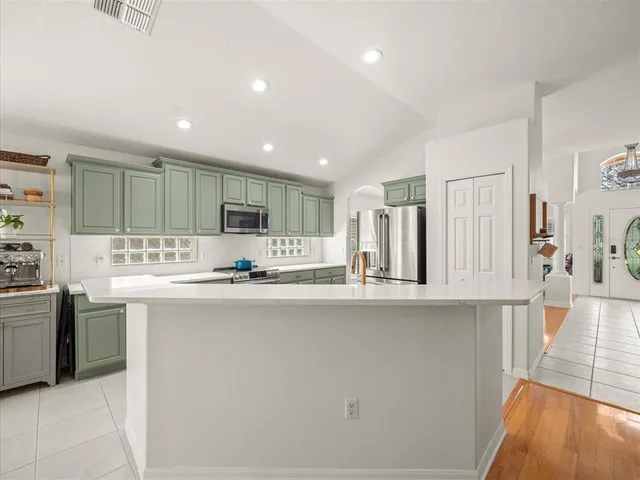 a large kitchen with stainless steel appliances granite countertop a lot of counter space and wooden floors