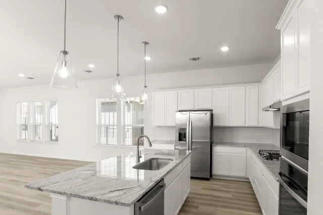 a large kitchen with stainless steel appliances kitchen island a large counter top and a stove top oven