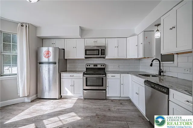 a kitchen with granite countertop a stove sink and refrigerator