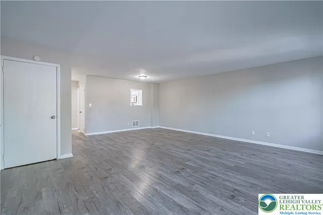 a view of an empty room with wooden floor and window