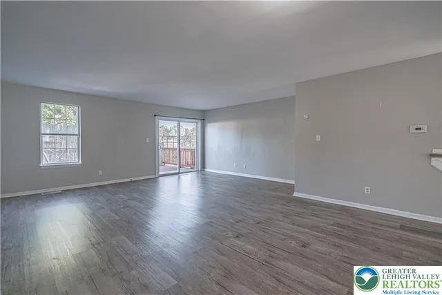 a view of an empty room with wooden floor and window