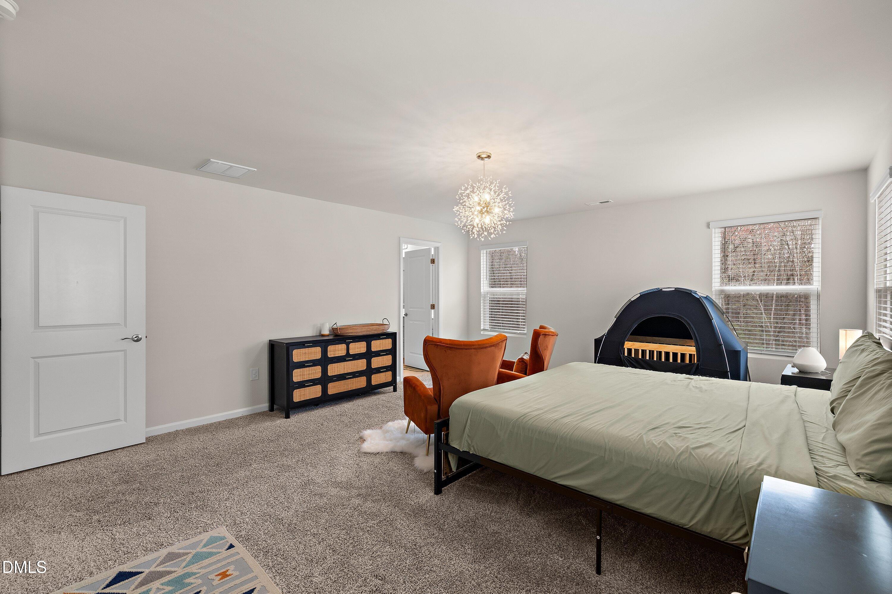 154 Anise Tree Way Clayton, NC 27527 - Photo 25 of 43 a bedroom with a bed and a chandelier