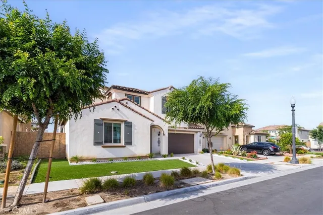 a front view of a house with a garden and trees