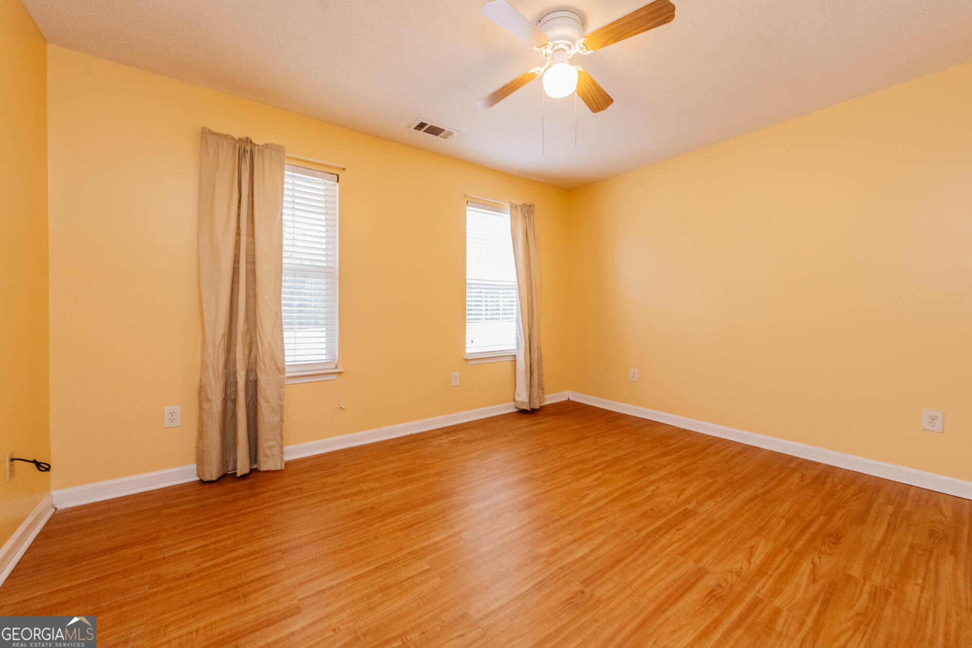 525 Hardison Church Road Byron, GA 31008 - Photo 12 of 32 an empty room with wooden floor chandelier fan and windows