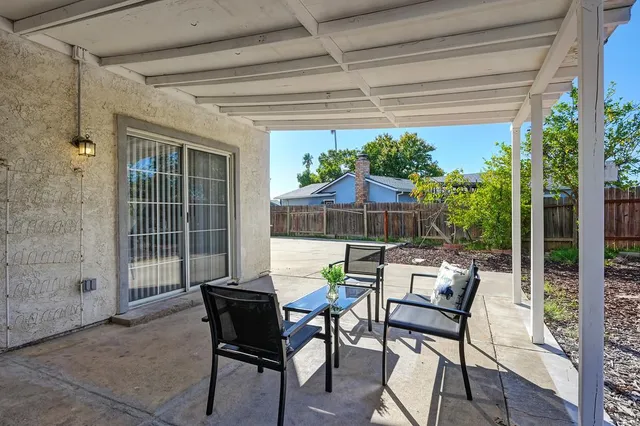 a patio with table and chairs with potted plants and wooden fence