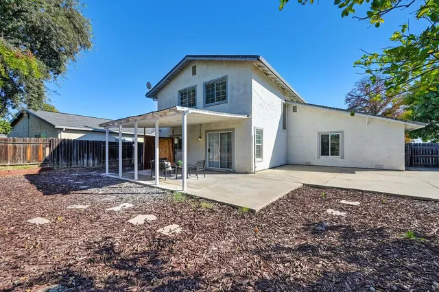 a patio with a table and chairs and potted plants