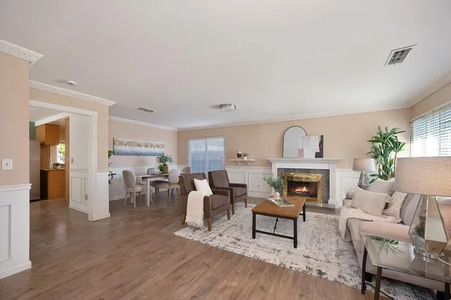 a living room with furniture a fireplace and a dining table with wooden floor