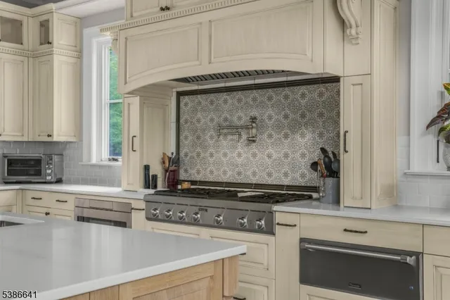 a kitchen with stainless steel appliances granite countertop a stove and a white cabinet