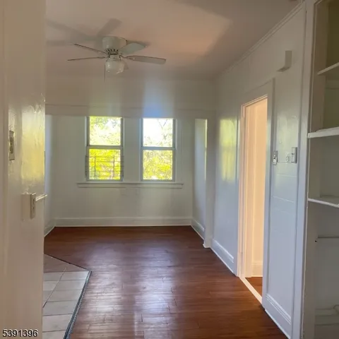 an empty room with wooden floor closet and windows
