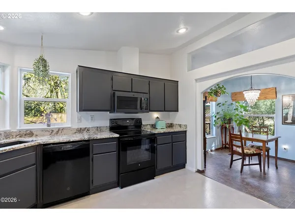 a kitchen with stainless steel appliances granite countertop a stove top oven a sink dishwasher a dining table and chairs with wooden floor
