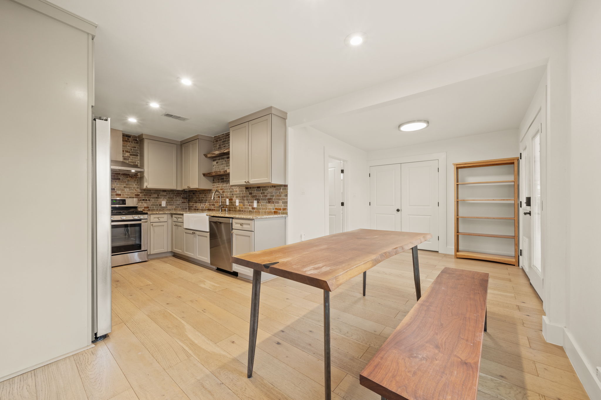 912 Mansell Avenue Austin, TX 78702 - Photo 12 of 37 Kitchen featuring open shelves, appliances with stainless steel finishes, light wood-type flooring, recessed lighting, and light stone counters