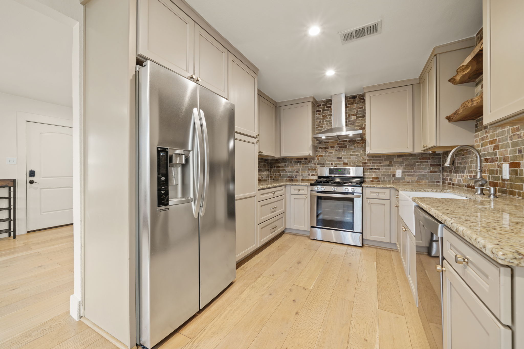 912 Mansell Avenue Austin, TX 78702 - Photo 4 of 37 Kitchen with open shelves, appliances with stainless steel finishes, light stone countertops, light wood finished floors, and recessed lighting