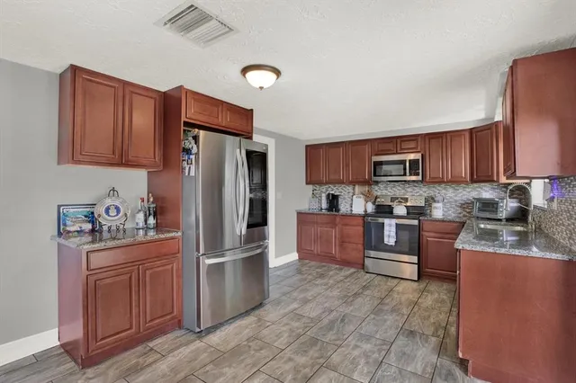 a kitchen with granite countertop a refrigerator stove top oven and sink