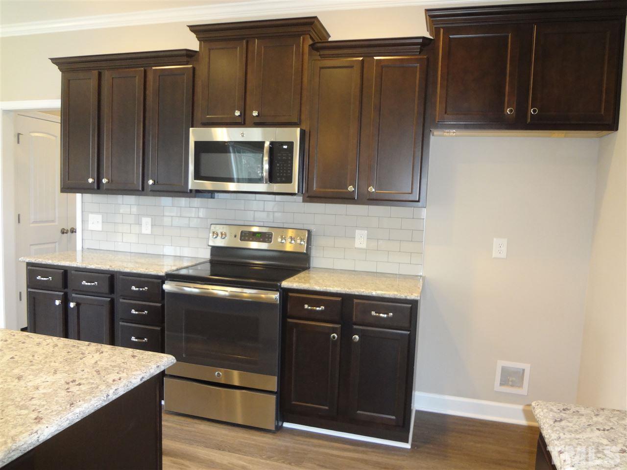 7932 Creech Road Middlesex, NC 27557 - Photo 3 of 25 a kitchen with stainless steel appliances granite countertop wooden cabinets and a stove top oven