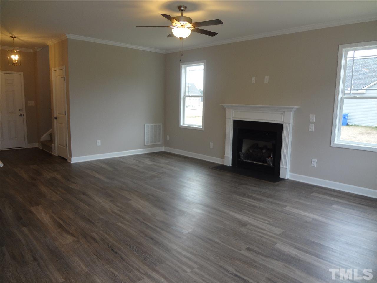 7932 Creech Road Middlesex, NC 27557 - Photo 8 of 25 an empty room with wooden floor fireplace and windows