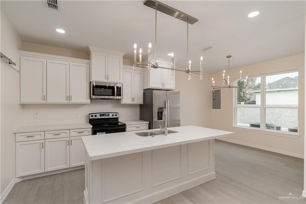 5406 North Crown Point Pharr, TX 78577 - Photo 6 of 14 a kitchen with kitchen island granite countertop a sink stainless steel appliances and white cabinets