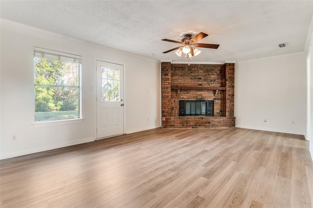 1308 Sundale Street Ennis, TX 75119 - Photo 2 of 12 wooden floor fireplace and windows in an empty room