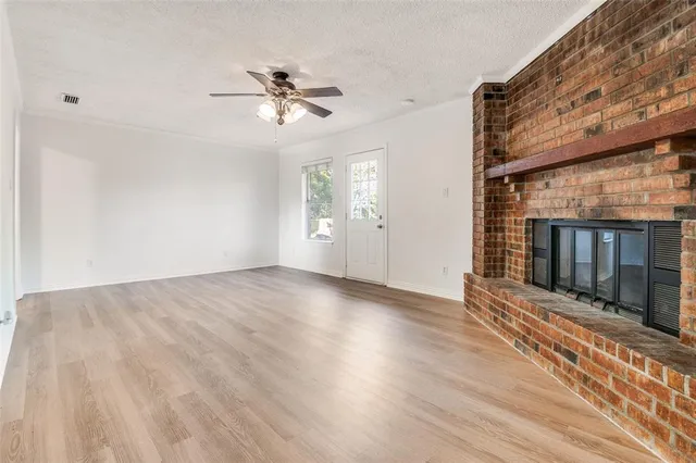 a view of a livingroom with wooden floor a ceiling fan and front door