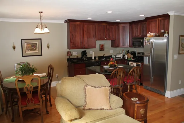 a kitchen with granite countertop a refrigerator a stove a dining table and chairs with wooden floor