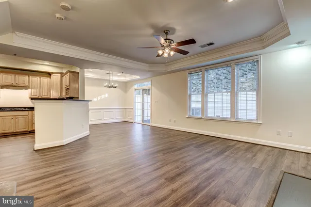 a view of empty room with wooden floor and fan
