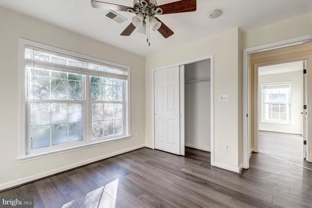 a view of an empty room with wooden floor fireplace and a window