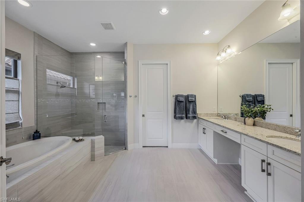 12762 Dundee Lane Naples, FL 34120 - Photo 18 of 35 a bathroom with a granite countertop sink a mirror a bathtub and shower