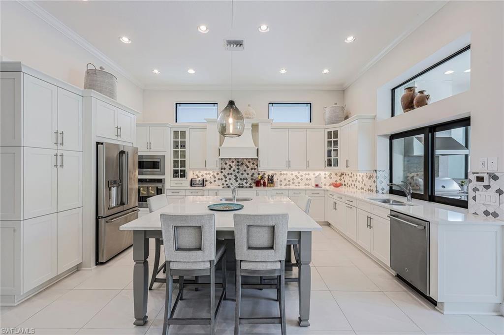 12762 Dundee Lane Naples, FL 34120 - Photo 8 of 35 a kitchen with stainless steel appliances kitchen island granite countertop a table chairs sink and cabinets