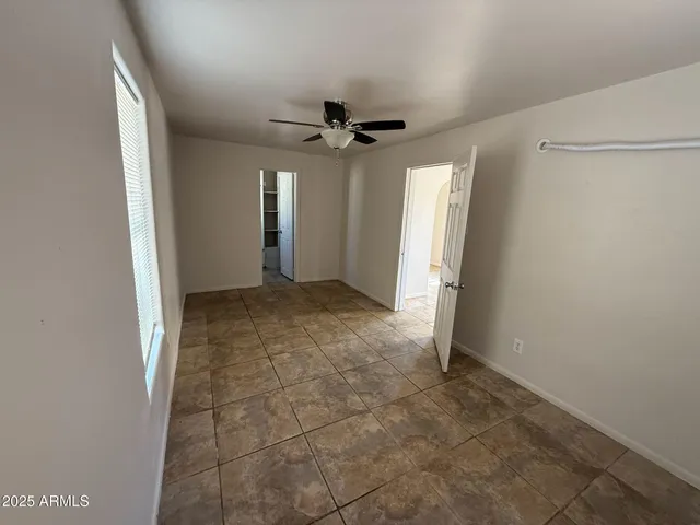 an empty room with a ceiling fan and carpet