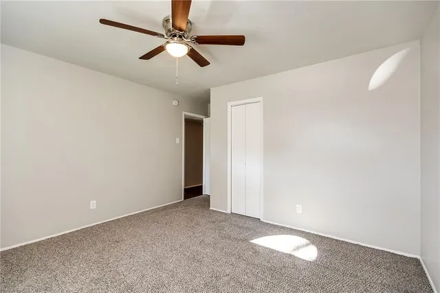 an empty room with closet and a chandelier fan