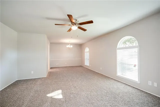 an empty room with windows and ceiling fan