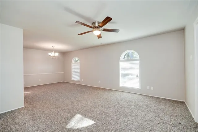 a view of a livingroom with a chandelier fan and windows