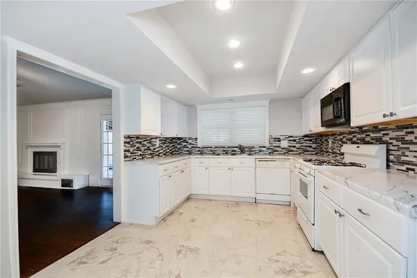 a kitchen with granite countertop white cabinets and stainless steel appliances