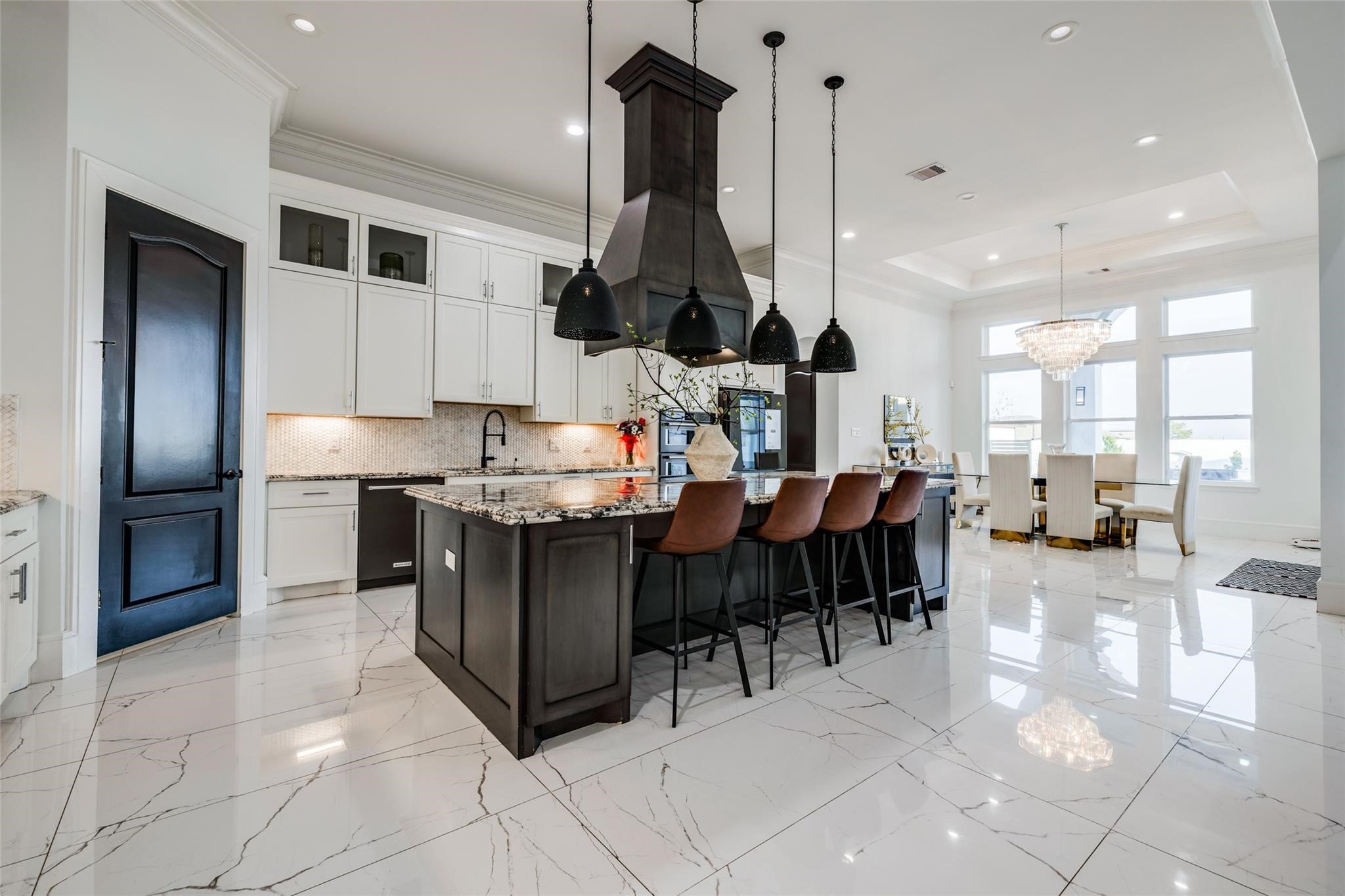 4821 Walters Road Richmond, TX 77469 - Photo 24 of 50 his designer gourmet kitchen makes a bold statement with soaring custom cabinetry, dramatic ceiling-height finishes, and an oversized waterfall island perfect for entertaining. Featuring premium stainless steel appliances, elegant pendant lighting, marble-style flooring, and rich contrasting accents, the space blends timeless sophistication with modern functionality. The open-concept layout, expansive prep areas, built-in wine storage, and abundant natural light create a luxurious culinary experience