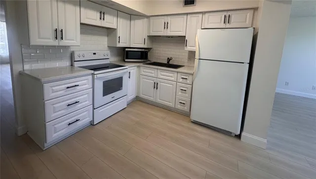 a kitchen with white cabinets and white appliances