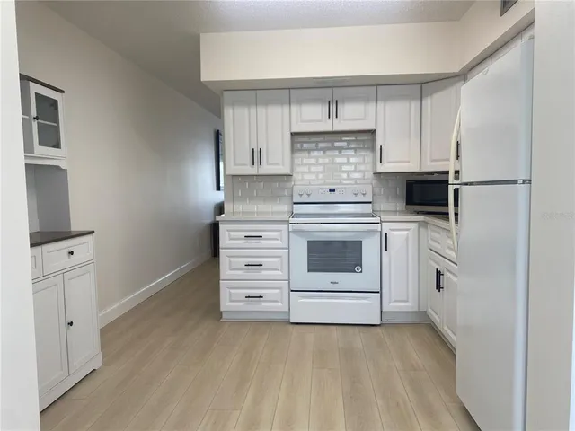 a kitchen with white cabinets and white appliances
