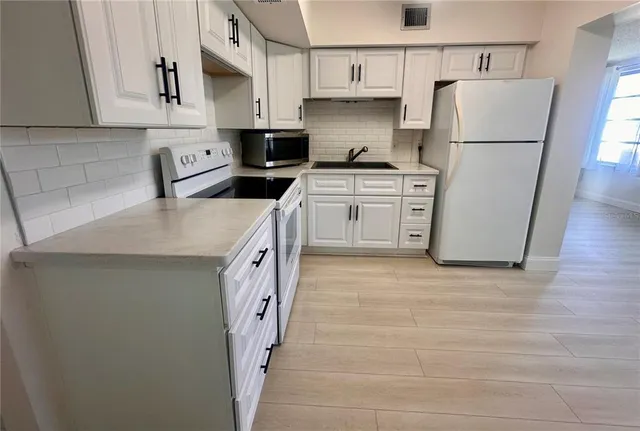 a view of a kitchen with electric appliances and cabinets