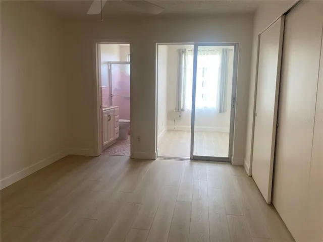 a view of an empty room with window and wooden floor