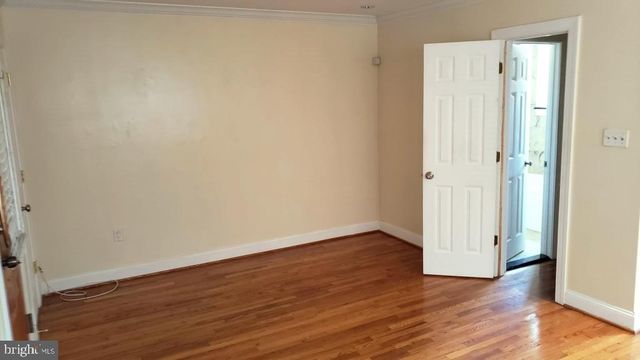 a view of an empty room with wooden floor and entrance