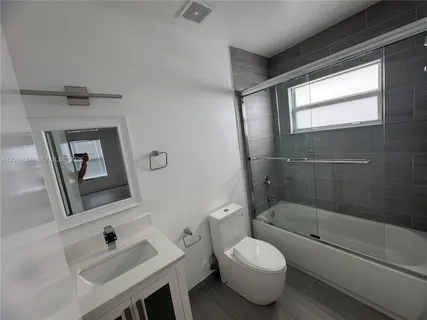 a bathroom with a sink toilet a mirror and bathtub